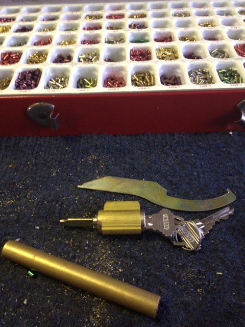 image of a lock cylinder removed from the lock and a container of cylinder pins in a variety of colors